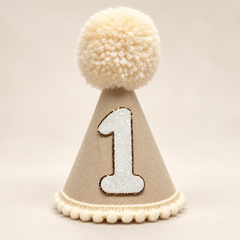 Tan first birthday party hat with cream pom pom and white glitter number one