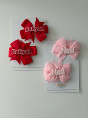 Personalized red and pink 3D name hair bow pairs on The Favored Atelier display cards