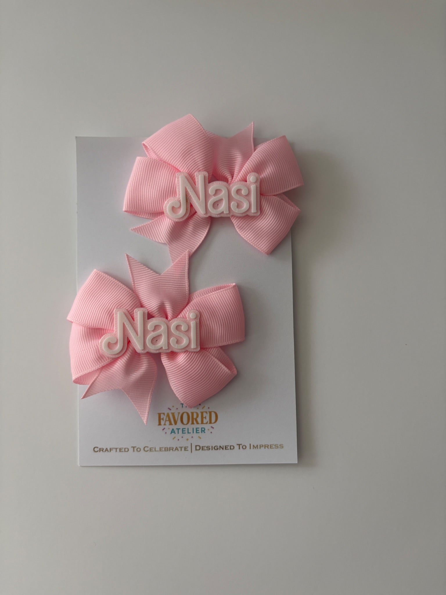 Close-up of pink personalized Nasi name hair bow pair