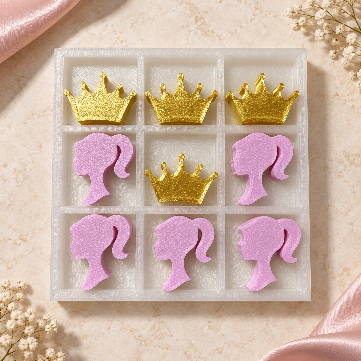 White tray tic-tac-toe set with pink girl silhouette pieces and gold crown pieces, angled view