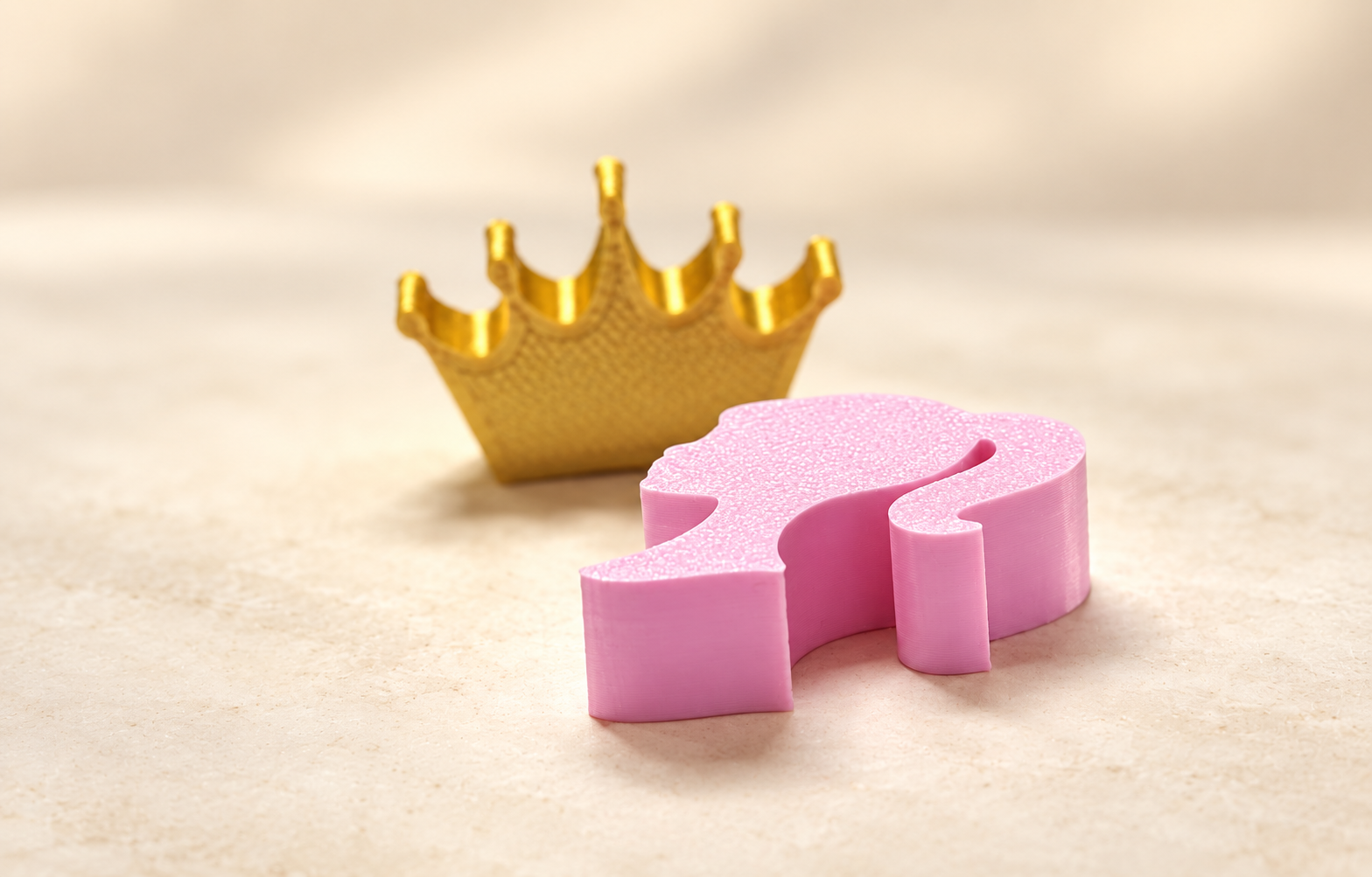 Close-up of a gold crown piece and pink girl silhouette piece