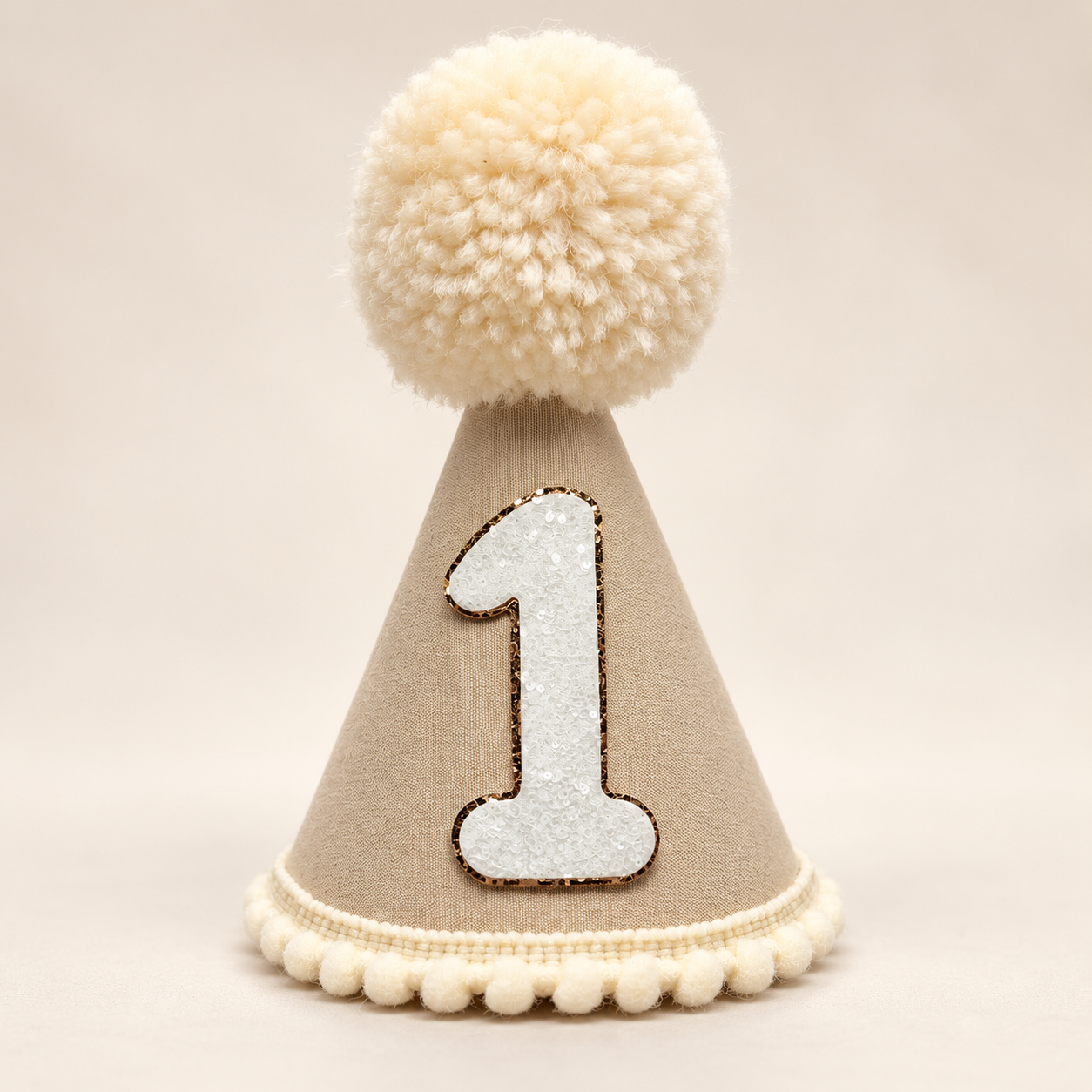 Tan first birthday party hat with cream pom pom and white glitter number one